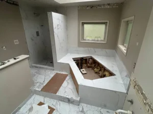 Marble-look porcelain tile installation on floor, walls and tub deck during bathroom renovation