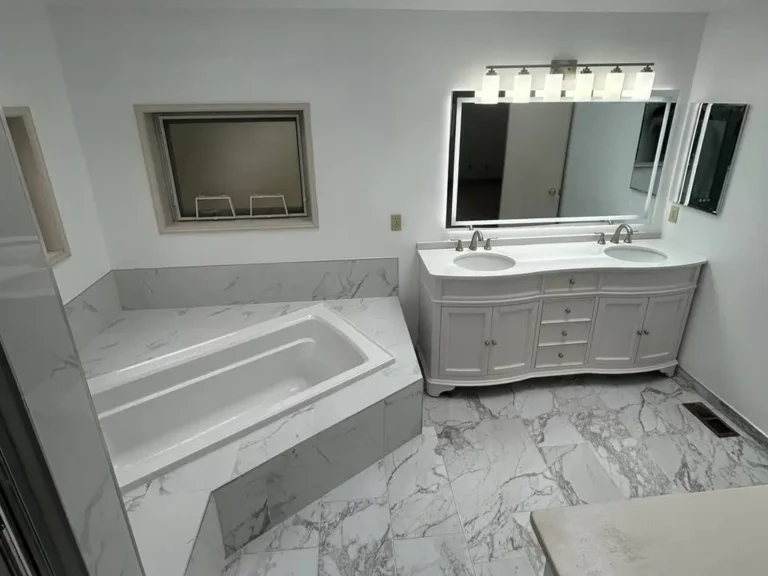 Finished master bathroom with marble tile, soaking tub and custom double-sink vanity with LED mirrors