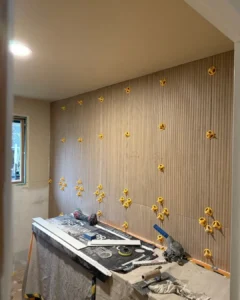 Fluted wood-look porcelain wall tile installation with leveling system during full bathroom renovation