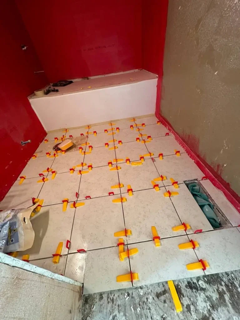 Porcelain tile floor being installed with leveling clips in a Seattle bathroom