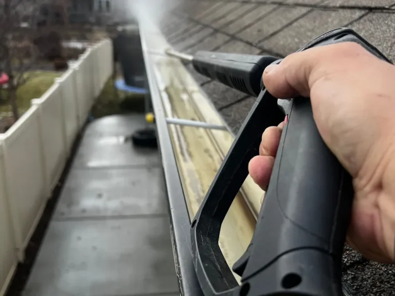 Gutter cleaning service: flushing a residential gutter with a pressure washer