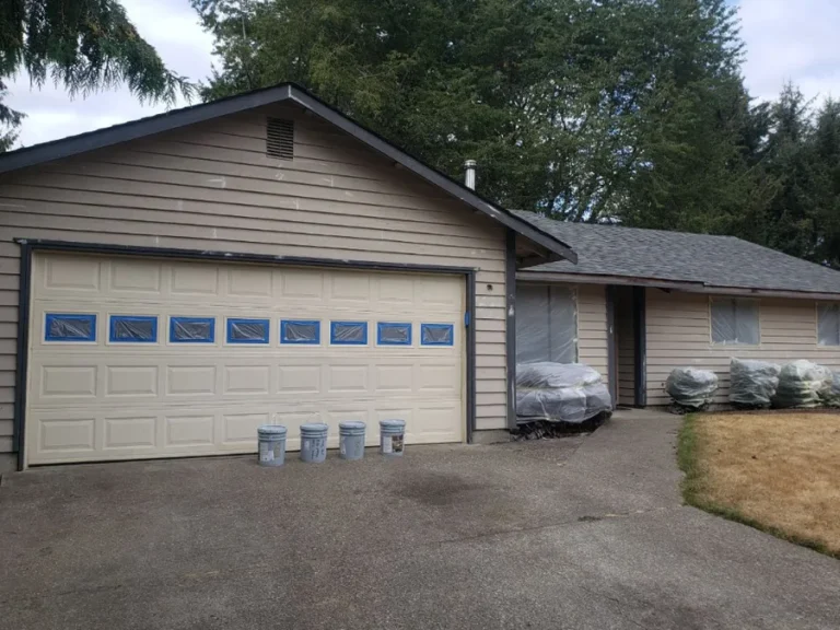 Before: beige rambler with attached garage, windows taped for painting