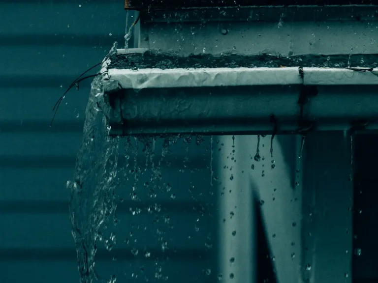 Rainwater overflowing a clogged gutter during a storm