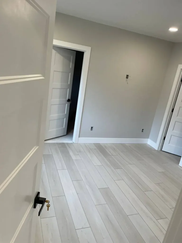Refinished light hardwood floor in a hallway with new baseboards
