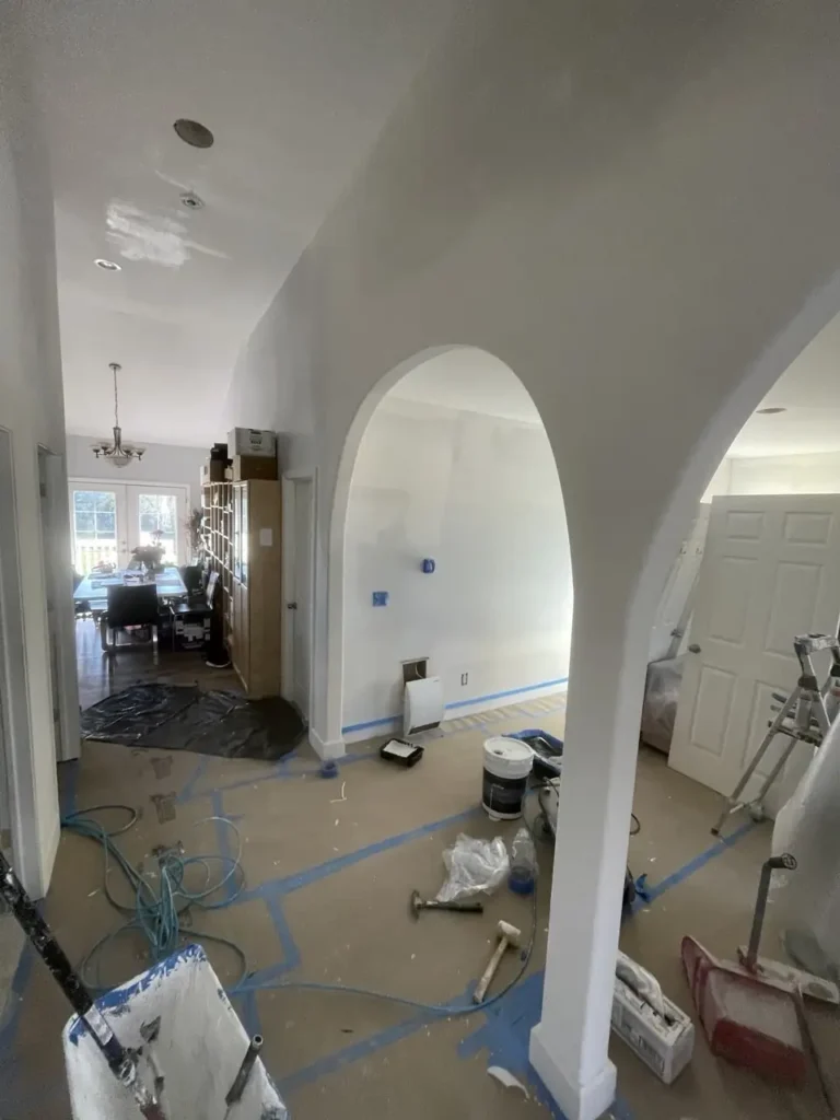 During: wood plank flooring being installed through arched living room
