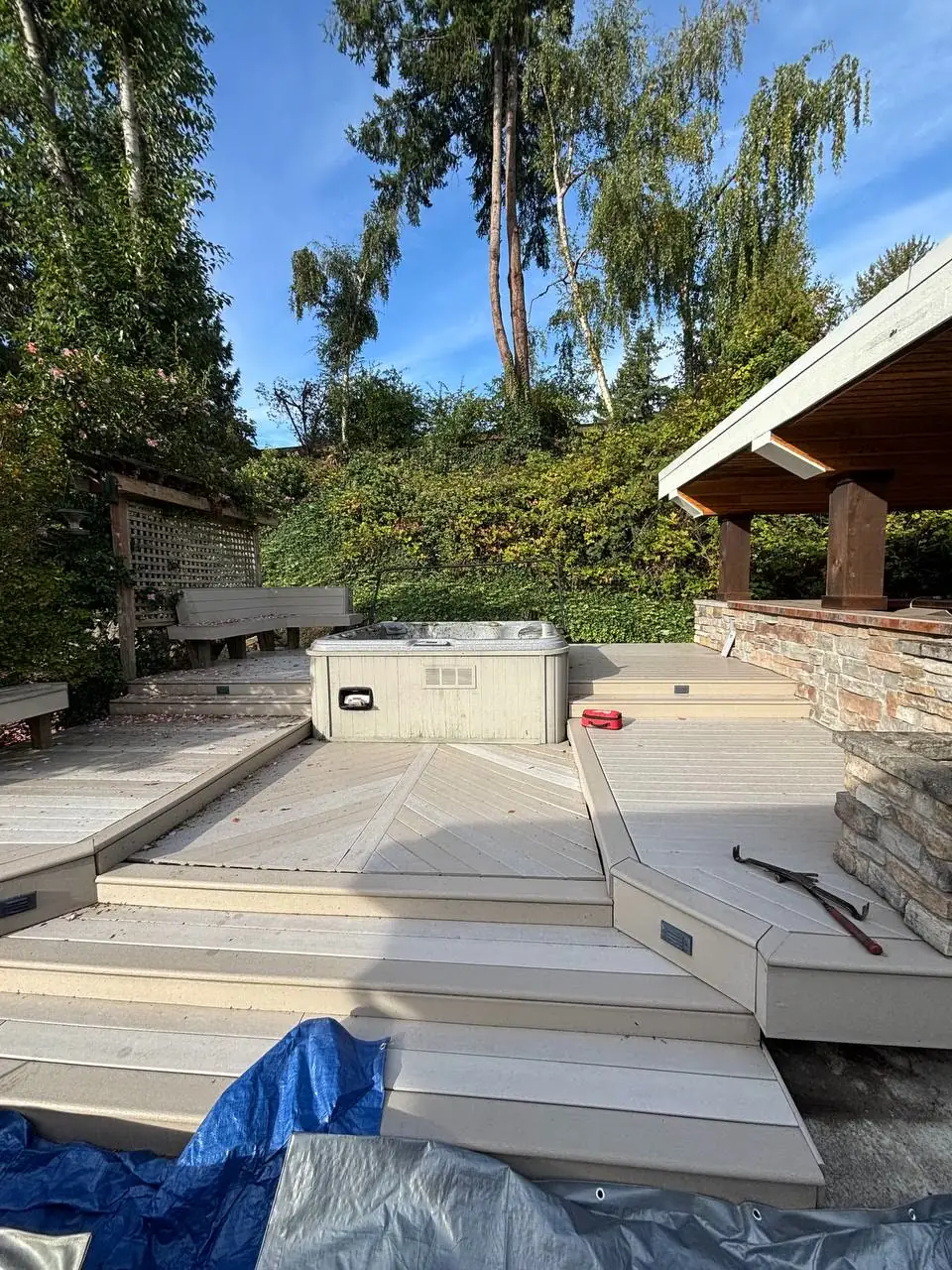After: multi-level composite deck with hot tub and stone outdoor kitchen