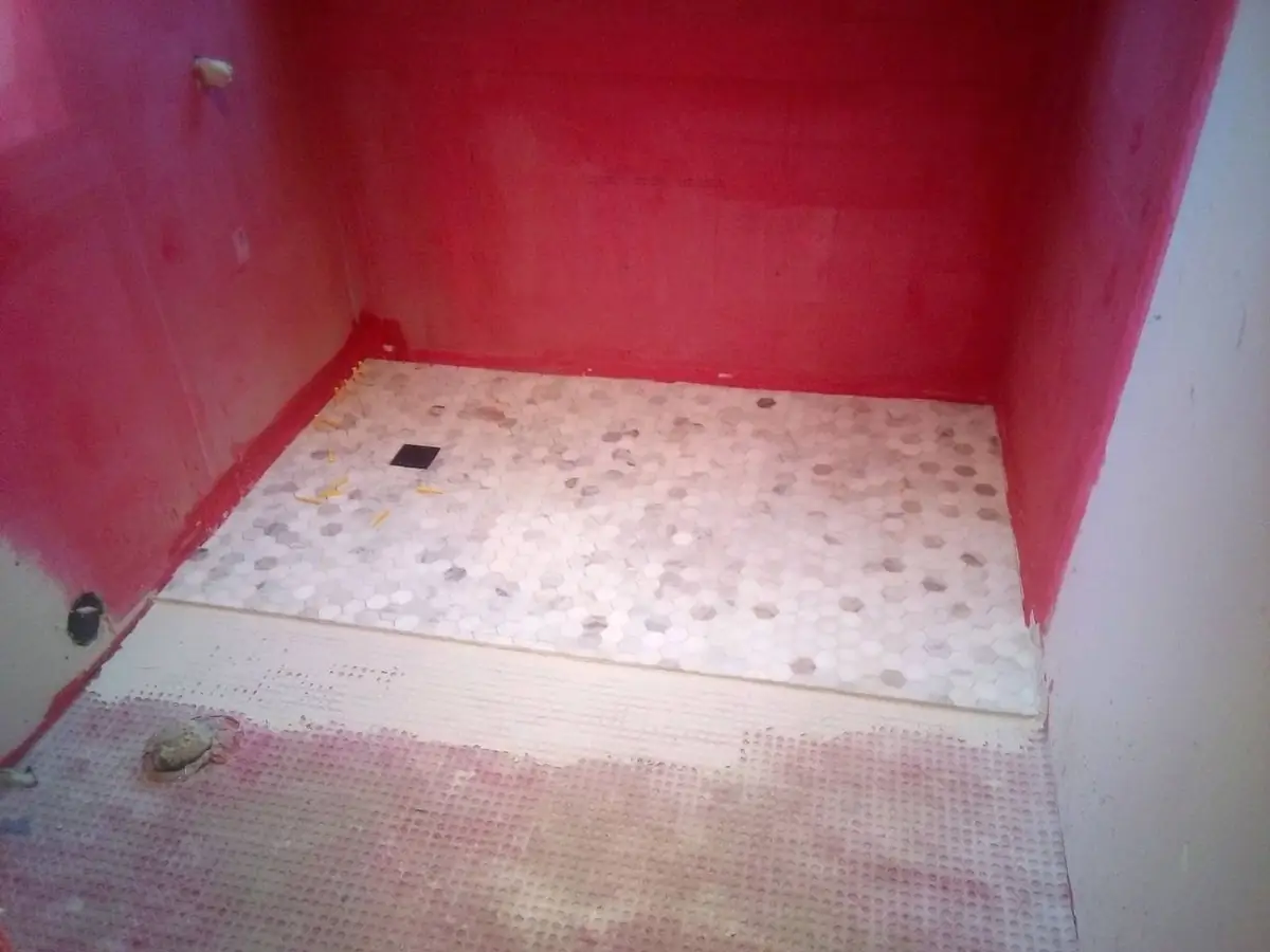 Mosaic tile shower pan being installed over waterproofing